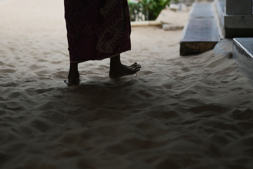 A woman walks on sand in Legung Timur village in Sumenep on Madura Island, Indonesia, Tuesday, Sept. 9, 2025. (AP Photo/Dita Alangkara)