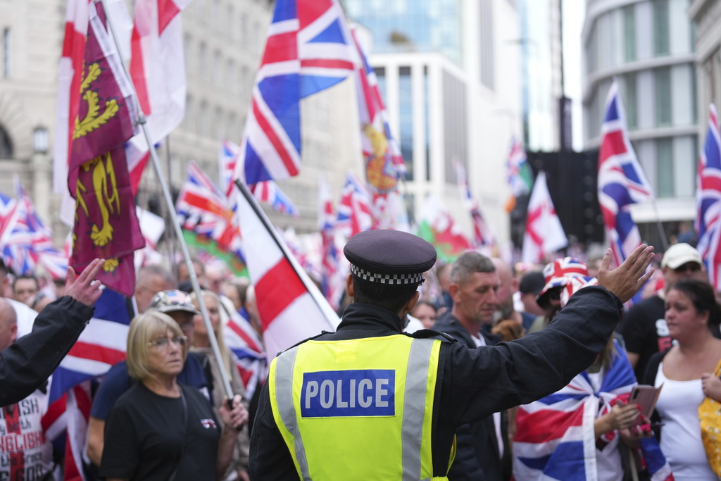 A police officer stands in front of demonstrators taking part in a Tommy Robinson-led Unite the Kingdom march and rally, in London, Saturday Sept. 13, 2025. (AP Photo/Joanna Chan)