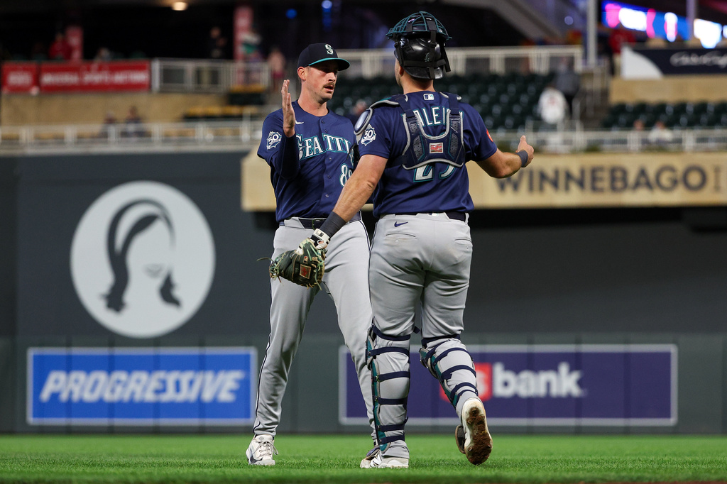Seattle Mariners pitcher Cooper Criswell, left, and catcher Cal Raleigh celebrates their teams win against the Minnesota Twins during the ninth inning of a baseball game, Tuesday, April 28, 2026, in Minneapolis. (AP Photo/Matt Krohn)