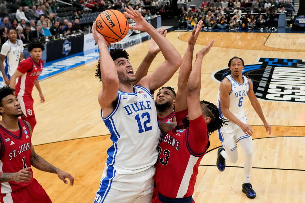 Duke forward Cameron Boozer (12) shoots over St. John's forward Bryce Hopkins (23) during the first half in the Sweet 16 of the NCAA college basketball tournament, Friday, March 27, 2026, in Washington. (AP Photo/Stephanie Scarbrough)