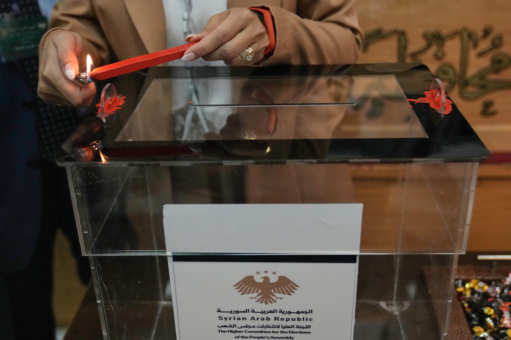 A Syrian election official burns red wax to stamp a ballot box ahead of the parliamentary elections at Latakia's Governor ballot station, in the coastal city of Latakia, Syria, Sunday, Oct. 5, 2025. (AP Photo/Hussein Malla)