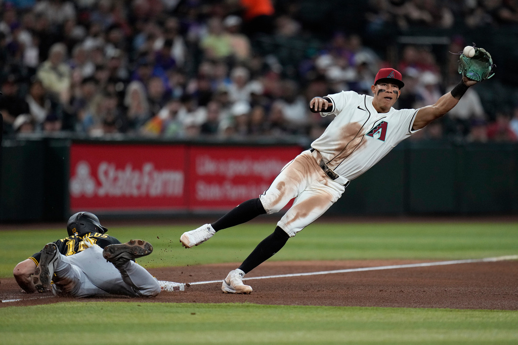 Arizona Diamondbacks third baseman Jose Fernandez, right, jumps after a wide pickoff throw as Pittsburgh Pirates' Bryan Reynolds, left, dives safely back to third base during the fifth inning of a baseball game, Thursday, May 7, 2026, in Phoenix. (AP Photo/Ross D. Franklin)