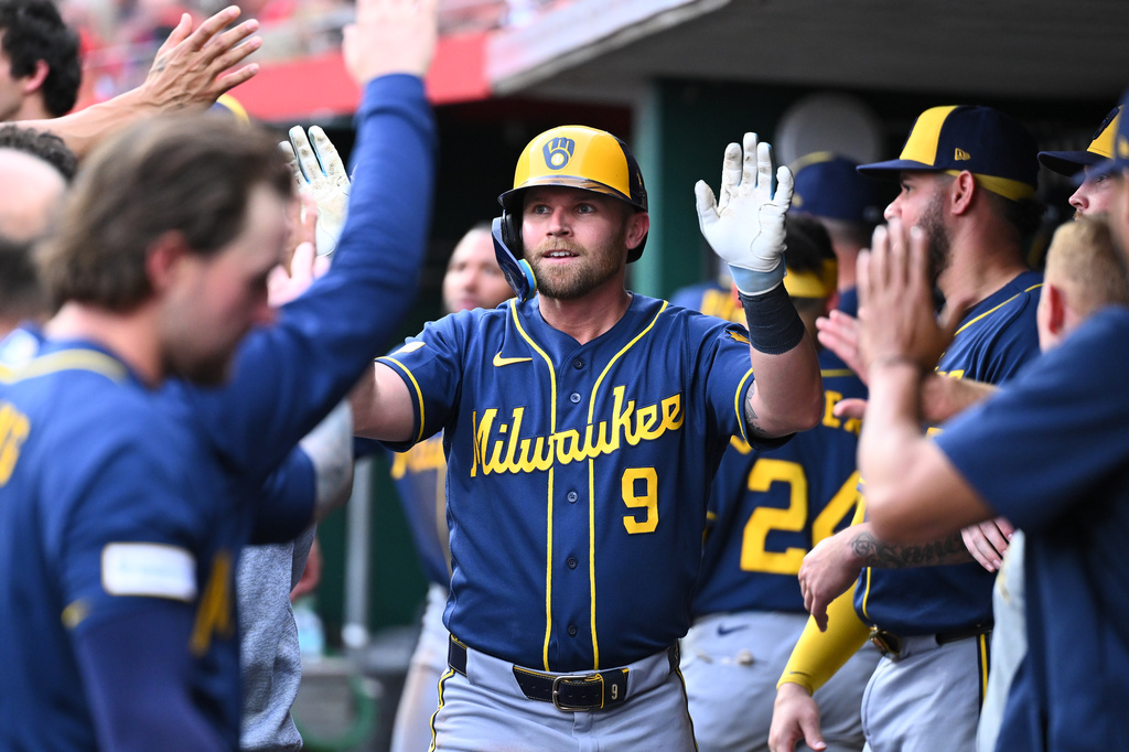 Milwaukee Brewers' Jake Bauers (9) high-fives his teammates after hitting a solo home run during the third inning of a baseball game against the Cincinnati Reds in Cincinnati, Wednesday, June 24, 2026. (AP Photo/Ben Jackson)