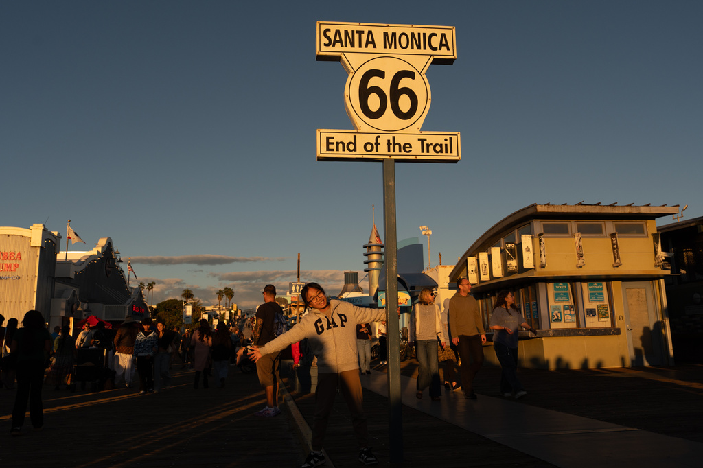 A visitor poses for photos with the "End of the Trail" Route 66 sign on the Santa Monica Pier in Santa Monica, Calif., Saturday, Nov. 22, 2025. (AP Photo/Jae C. Hong)
