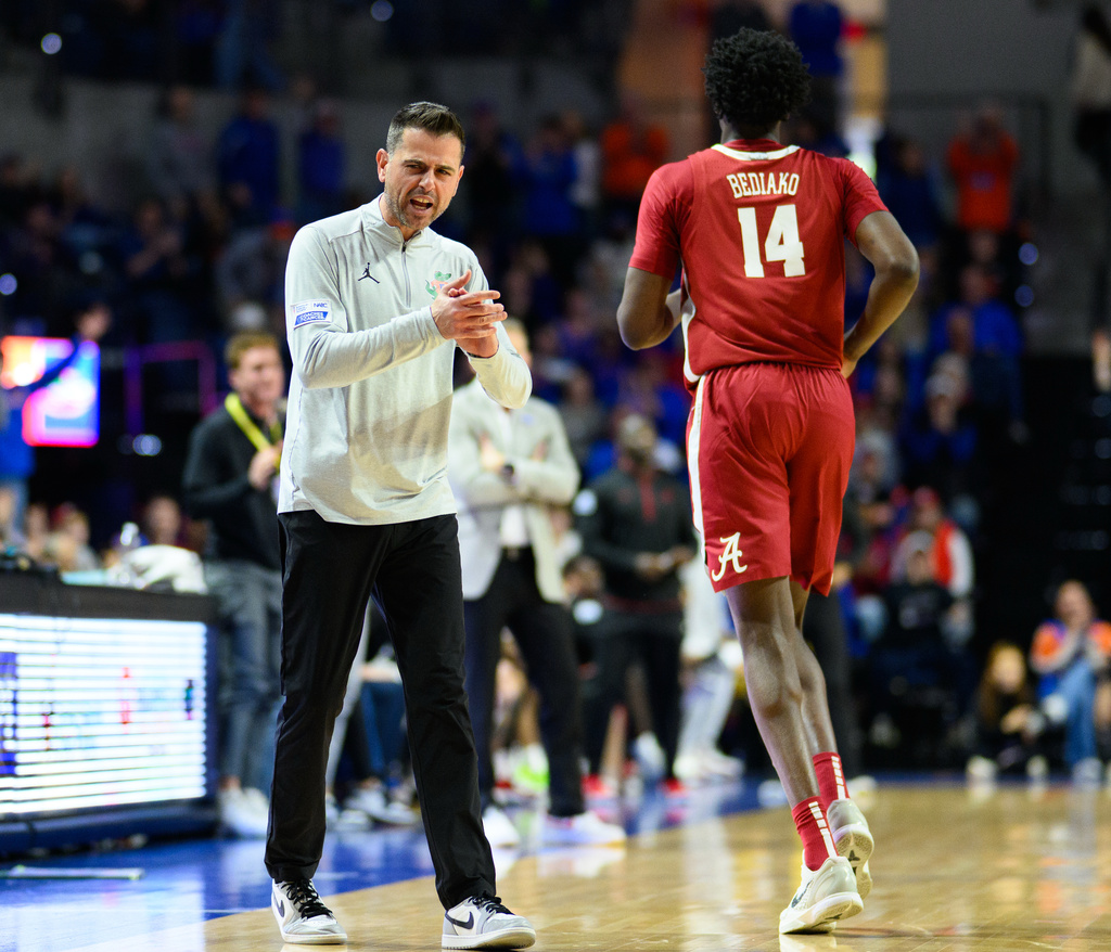Florida head coach Todd Golden, left, claps and talks to Alabama center Charles Bediako (14) who walks off the court after fouling out during the second half of an NCAA college basketball game, Sunday, Feb. 1, 2026, in Gainesville, Fla. (AP Photo/Noah Lantor)