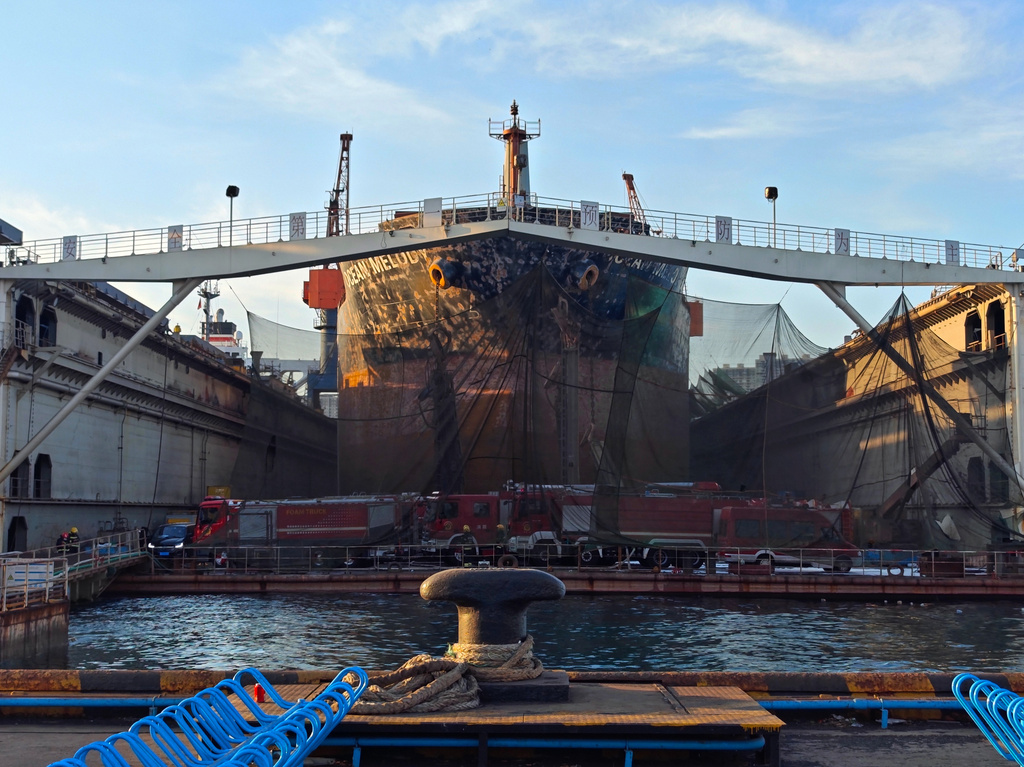 In this photo released by Xinhua News Agency, firefighters' vehicles parked near a repair cargo ship after it caught fire at a port in Qingdao, east China's Shandong Province, Thursday, Sept. 10, 2026. (Li Aoqiu/Xinhua via AP)