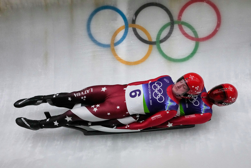 Latvia's Martins Bots, left, and Roberts Plume, right, slide down the track during a men's doubles luge run at the 2026 Winter Olympics, in Cortina d'Ampezzo, Italy, Wednesday, Feb. 11, 2026. (AP Photo/Aijaz Rahi)
