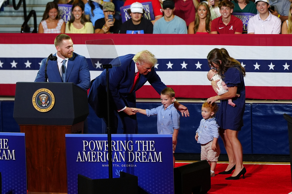President Donald Trump, center, invites a family on stage to speak about Trump Accounts at Wheeler High School, Wednesday, July 22, 2026, in Marietta, Ga. (AP Photo/Julia Demaree Nikhinson)
