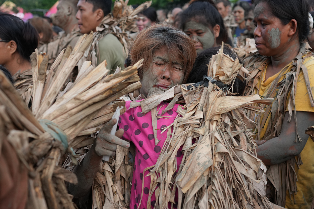 Catholic devotee covered in mud and dried banana leaves reacts as they participate at the mud people festival on the feast day of Saint John the Baptist at Bibiclat, Nueva Ecija province, northern Philippines on Wednesday, June 24, 2026. (AP Photo/Aaron Favila)