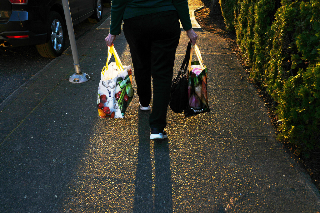 FILE - A woman carries reuable shopping bags to her car on Monday, March 16, 2026, in Portland, Ore. (AP Photo/Jenny Kane, File)