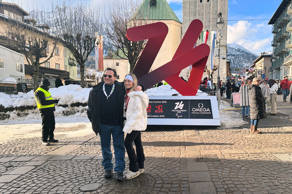 Karli Poliziani, center right, poses for a photo with her father, Len, as the temperature rose in the host city, during the 2026 Winter Olympics, in Cortina d'Ampezzo, Italy, Sunday, Feb. 8, 2026. (AP Photo/ Jennifer McDermott)