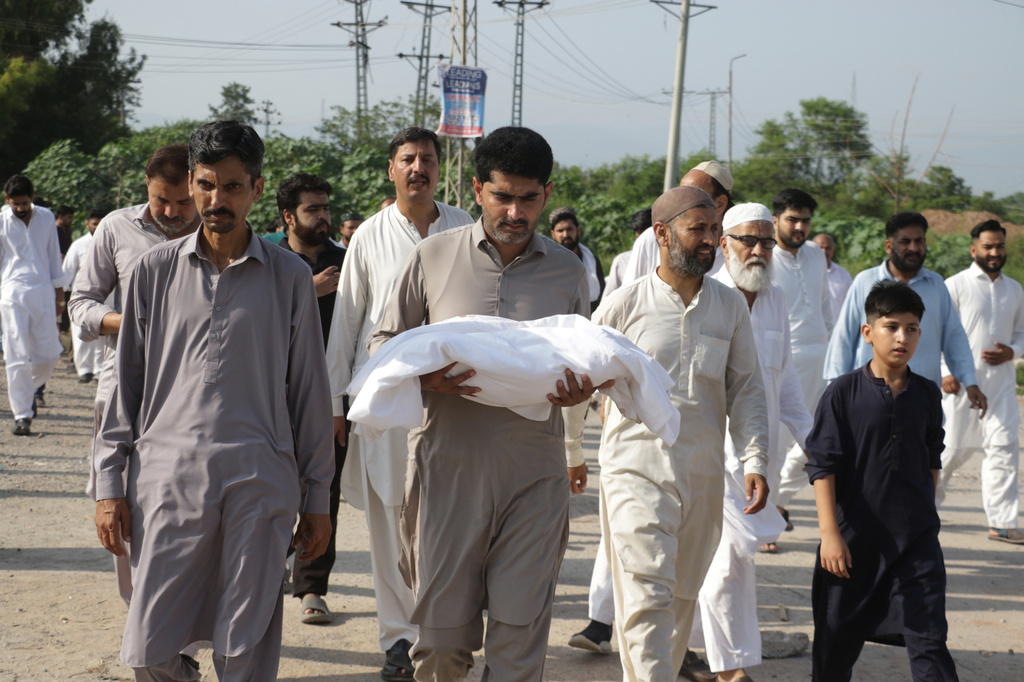 A man carries the body of a newborn for burial after the child died in a fire at a hospital in Islamabad, Pakistan, Wednesday, Aug. 26, 2026. (AP Photo/Ehsan Shahzad)