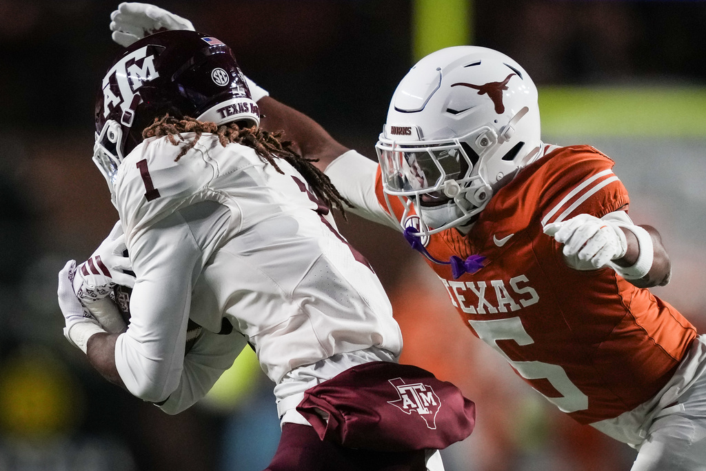 Texas defensive back Malik Muhammad (5) goes to tackle Texas A&M wide receiver Mario Craver (1) during the first quarter of an NCAA college football game in the Lone Star Showdown in Austin, Texas, Friday, Nov. 28, 2025. (Sara Diggins/Austin American-Statesman via AP)