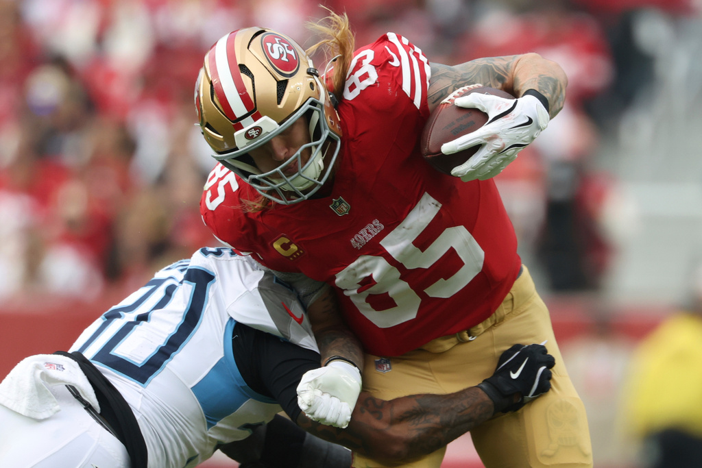 FILE - San Francisco 49ers tight end George Kittle (85) breaks a tackle by Tennessee Titans safety Kendell Brooks, left, during the first half of an NFL football game, Sunday, Dec. 14, 2025, in Santa Clara, Calif. (AP Photo/Jed Jacobsohn, File)