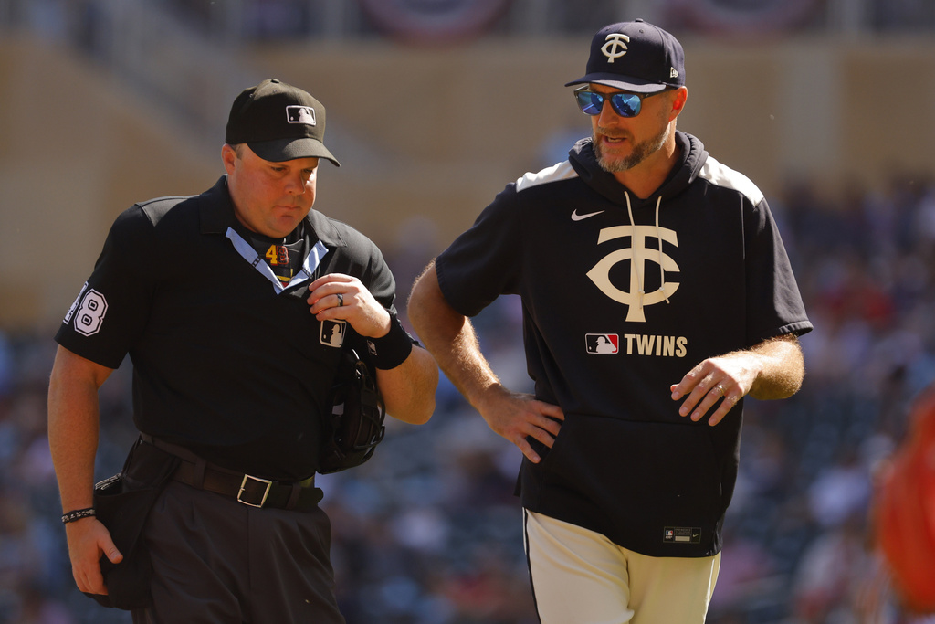 Minnesota Twins manager Rocco Baldelli speaks with home plate umpire Nick Mahrley, left, after a runner's interference call was awarded to the Cleveland Guardians on a play in the first inning of a baseball game Sunday, Sept. 21, 2025, in Minneapolis. (AP Photo/Bruce Kluckhohn)