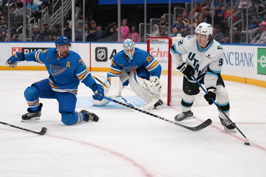 Utah Mammoth's Logan Cooley (92) looks to pass as Justin Faulk, left, and goaltender Jordan Binnington (50) defend during the third period of an NHL hockey game Thursday, Oct. 23, 2025, in St. Louis. (AP Photo/Jeff Roberson)