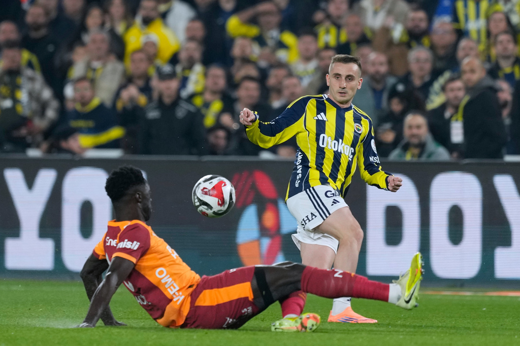 Fenerbahce's Kerem Akturkoglu, right, fights for the ball with Galatasaray's Davinson Sanchez during a Turkish Super Lig soccer match between Fenerbahce and Galatasaray, in Istanbul, Turkey, Monday, Dec. 1, 2025. (AP Photo/Khalil Hamra)