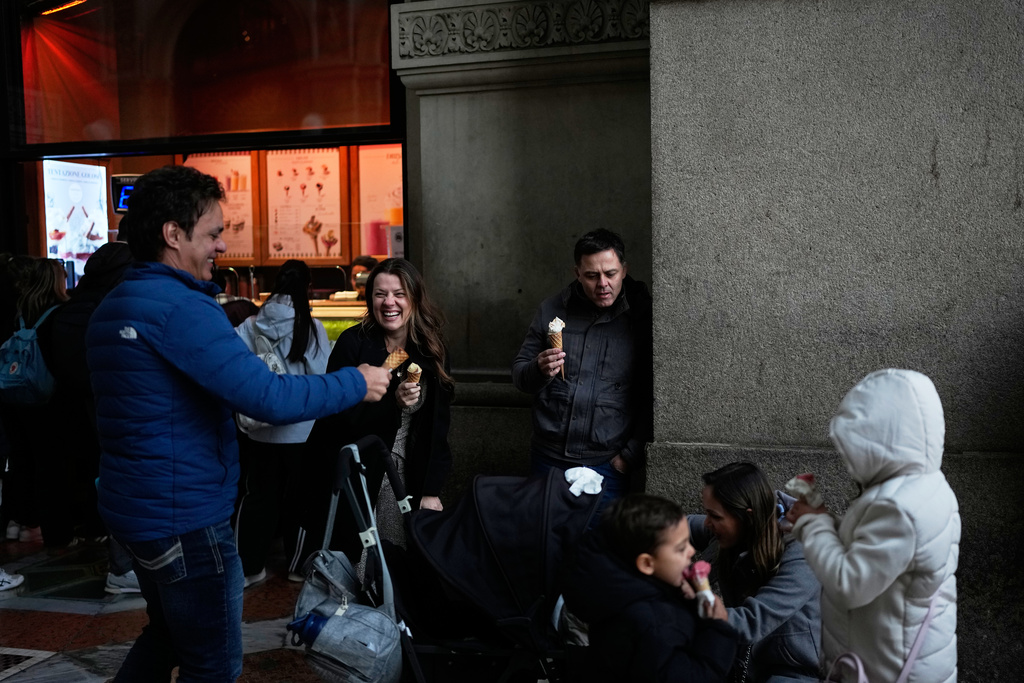 Tourists enjoy ice cream at the Galleria Vittorio Emanuele II, in Milan, Italy, Monday, Feb. 9, 2026. (AP Photo/Christophe Ena)