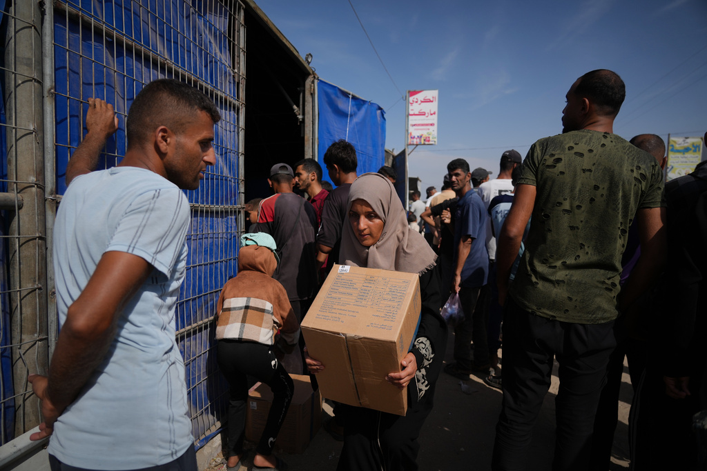 A Palestinian woman carries a box of food from the World Food Programme (WFP) after collecting it in Khan Younis, southern Gaza Strip, Sunday, Nov. 2, 2025. (AP Photo/Jehad Alshrafi)