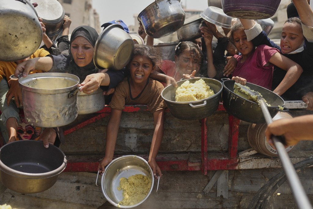 Palestinians struggle to get donated food at a community kitchen in Gaza City, northern Gaza Strip, Saturday, Aug. 16, 2025. (AP Photo/Jehad Alshrafi)