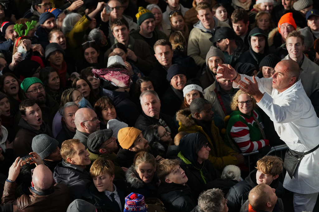 A piece of meat is thrown to the buyer in the crowd during the annual Christmas Eve meat auction at Smithfield Market in London, Wednesday, Dec. 24, 2025. (AP Photo/Kirsty Wigglesworth)