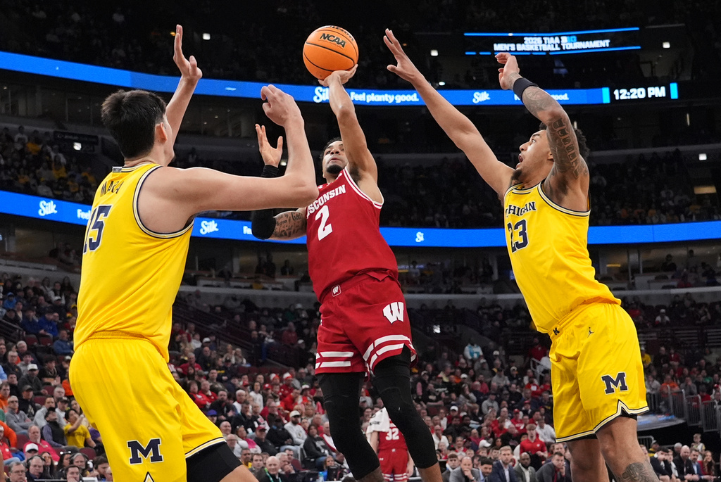 Wisconsin guard Nick Boyd, center, shoots between Michigan center Aday Mara, left, and forward Yaxel Lendeborg during the first half of an NCAA college basketball game in the semifinals of the Big 10 Conference tournament, Saturday, March 14, 2026, in Chicago. (AP Photo/Nam Y. Huh)