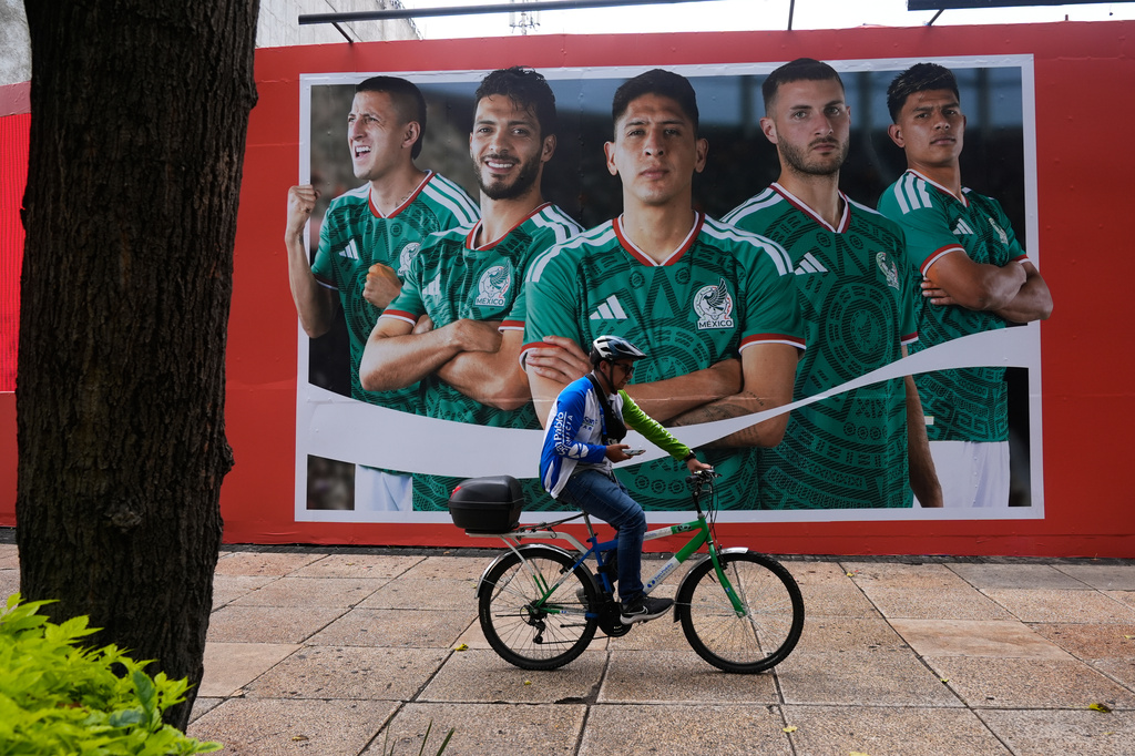A cyclist passes by a photo of Mexico's national soccer team players in Mexico City, Tuesday, June 9, 2026. (AP Photo/Marco Ugarte)