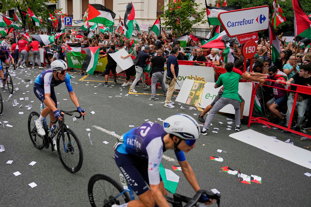 FILE - Riders of the Israel Premier Tech team compete as people holding Palestinian flags try to disrupt the eleventh stage of the Spanish Vuelta cycling race, from Bilbao to Bilbao, Spain, Wednesday, Sept. 3, 2025. (AP Photo/Miguel Oses, file)