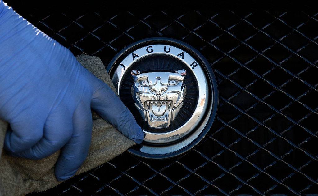 FILE - A worker polishes a Jaguar logo on a car at a Jaguar dealer in London, Wednesday Sept. 28, 2016. (AP Photo/Frank Austin, File)