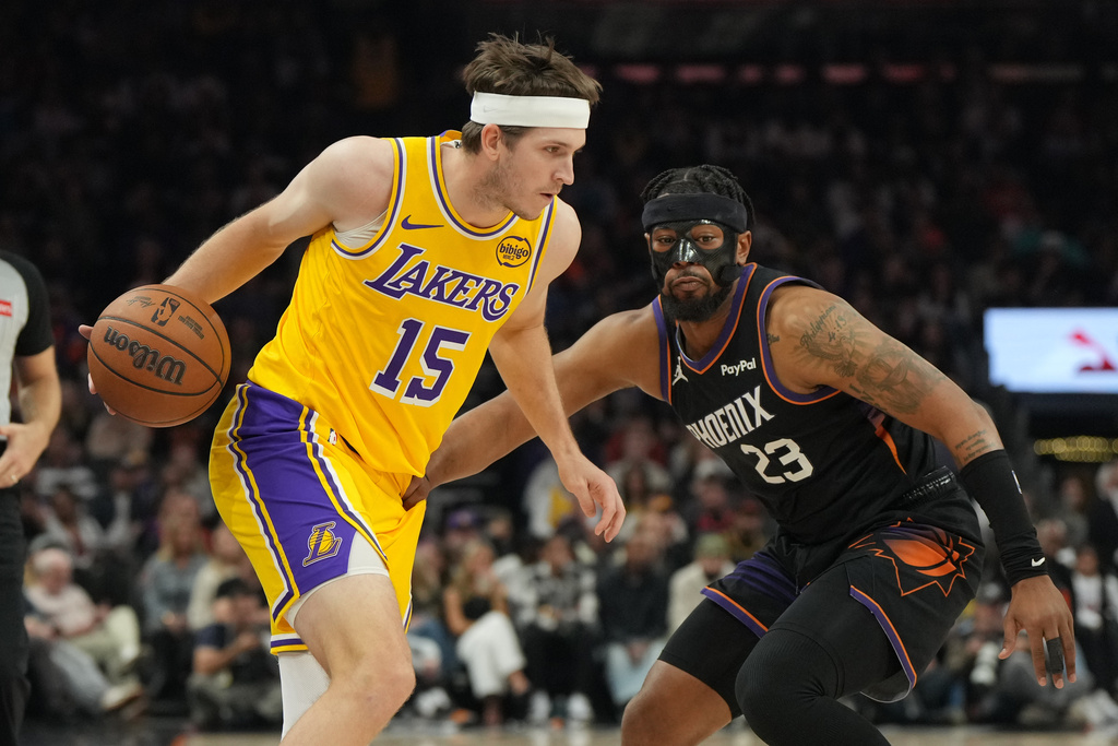 Los Angeles Lakers guard Austin Reaves shields the ball from Phoenix Suns guard Jordan Goodwin (23) during the first half of an NBA basketball game, Tuesday, Dec. 23, 2025, in Phoenix. (AP Photo/Rick Scuteri)