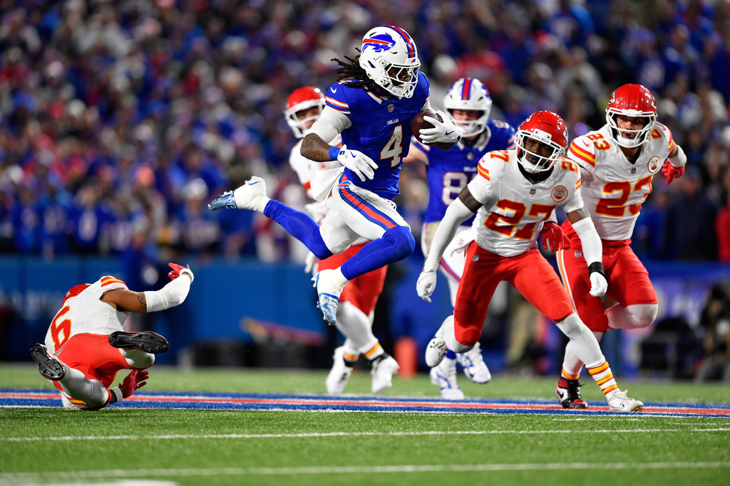Buffalo Bills running back James Cook III (4) runs with the ball as Kansas City Chiefs safety Bryan Cook (6), defensive back Chamarri Conner (27) and Drue Tranquill (23) defend during the first half of an NFL football game Sunday, Nov. 2, 2025, in Orchard Park. N.Y. (AP Photo/Adrian Kraus)