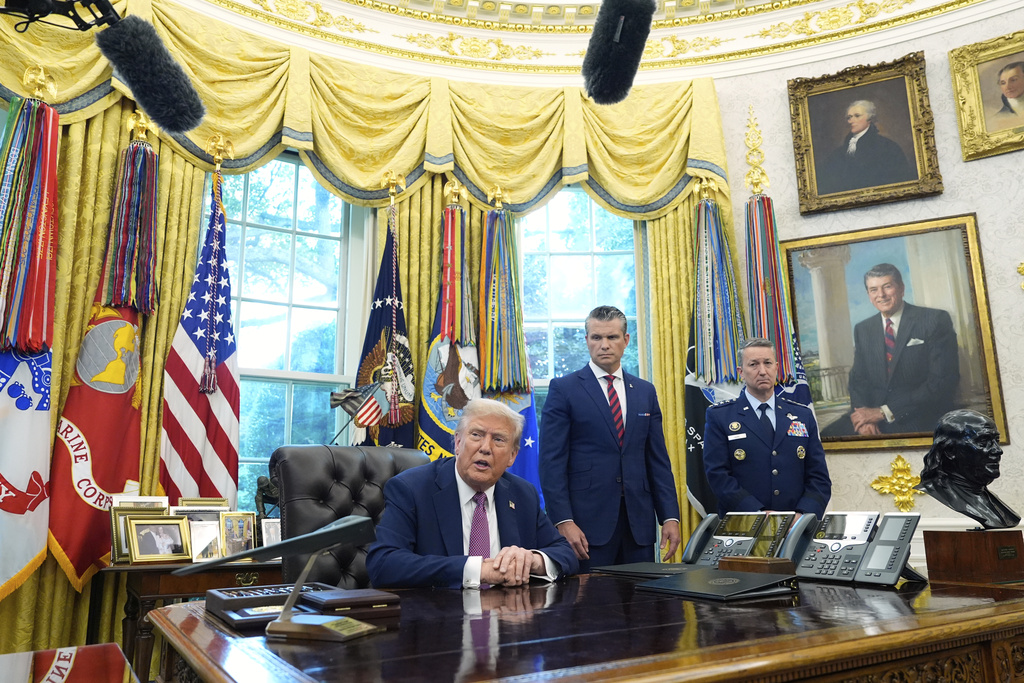 President Donald Trump speaks in the Oval Office of the White House, Friday, Sept. 5, 2025, in Washington, as Defense Secretary Pete Hegseth and Chairman of the Joint Chiefs of Staff Gen. Dan Caine listen. (AP Photo/Alex Brandon)