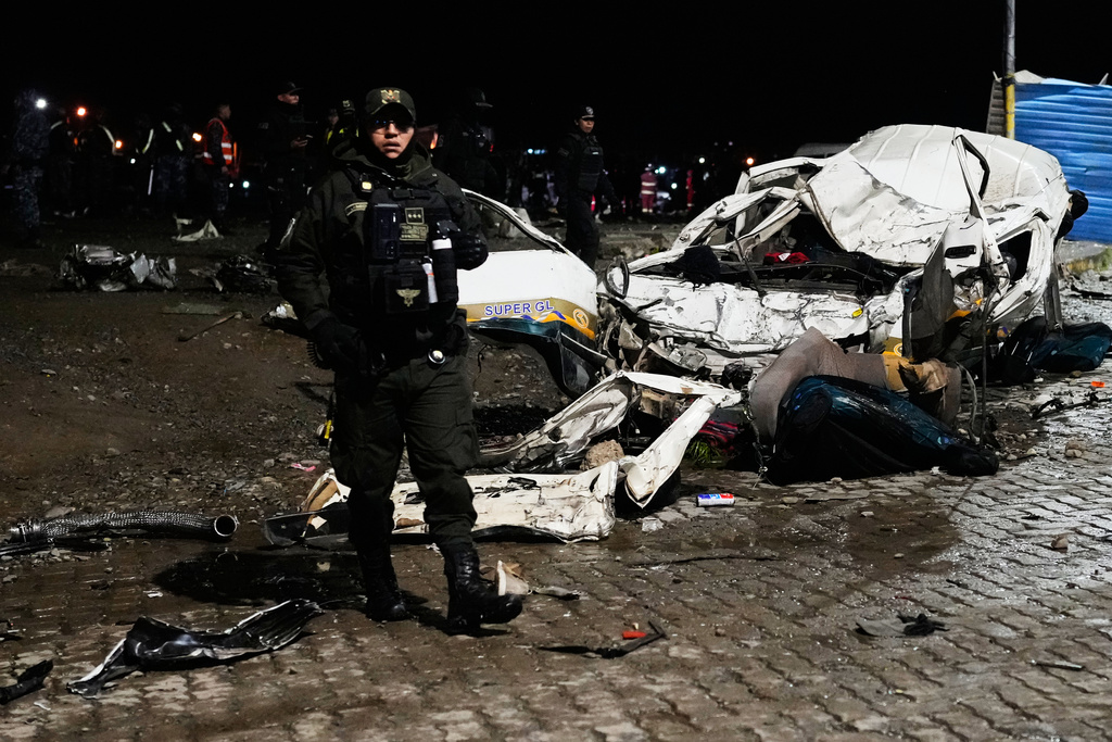 Police stands near a destroyed car that was struck by a plane in El Alto, Bolivia, Friday, Feb. 27, 2026. (AP Photo/Juan Karita)