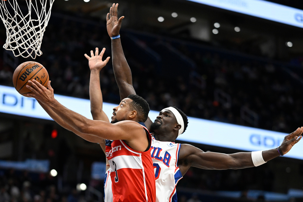 Washington Wizards guard CJ McCollum, left, rises past Philadelphia 76ers center Adem Bona for a basket during the first half of an NBA basketball game Tuesday, Oct. 28, 2025, in Washington. (AP Photo/John McDonnell)