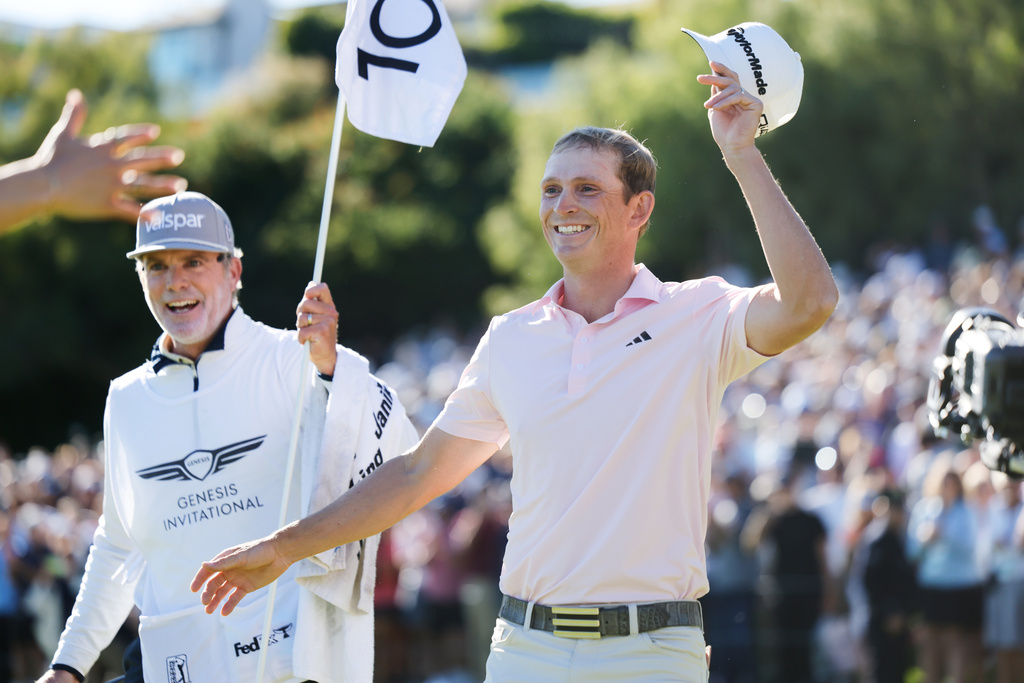 Jacob Bridgeman smiles next to caddie GW Cable after winning the Genesis Invitational golf tournament at Riviera Country Club, Sunday, Feb. 22, 2026, in the Pacific Palisades area of Los Angeles. (AP Photo/Caroline Brehman)