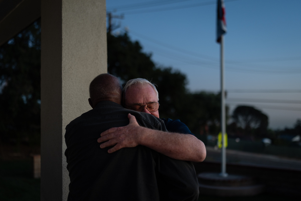 Ted Koerner, behind, hugs his neighbor Ellaird Bailey after Los Angeles County approved Bailey's rebuilding plans in Altadena, Calif., as they stand at Koerner's rebuilt home, Thursday, Dec. 11, 2025. (AP Photo/Jae C. Hong)
