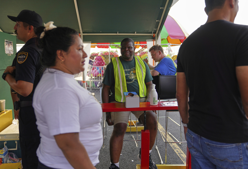Roger Atchou, center, a father of two from Togo volunteers at the St. Jude Catholic Church's Sweet Corn Festival on Saturday, Aug. 9, 2025, in Cedar Rapids, Iowa. (AP Photo/Jessie Wardarski)