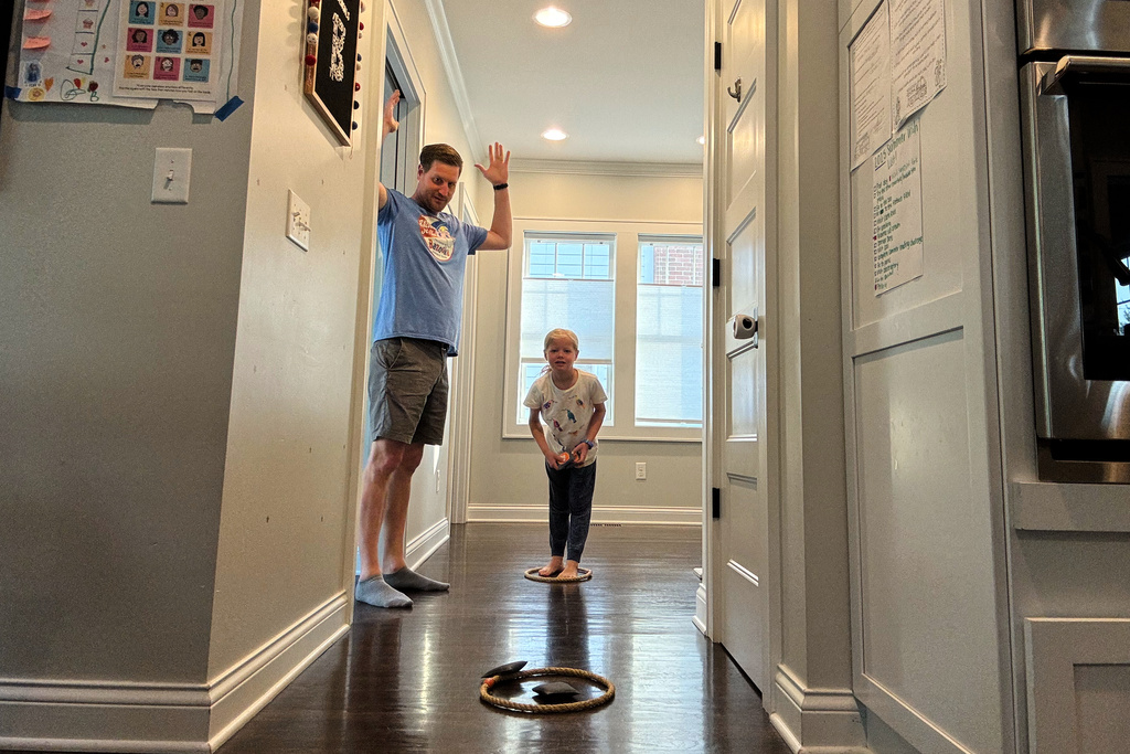 In this image provided by Future Fans, Mike and Ella Schroder play a bean bag toss game, June 2, 2025, in Columbus, Ohio. (Sara Schroder via AP)