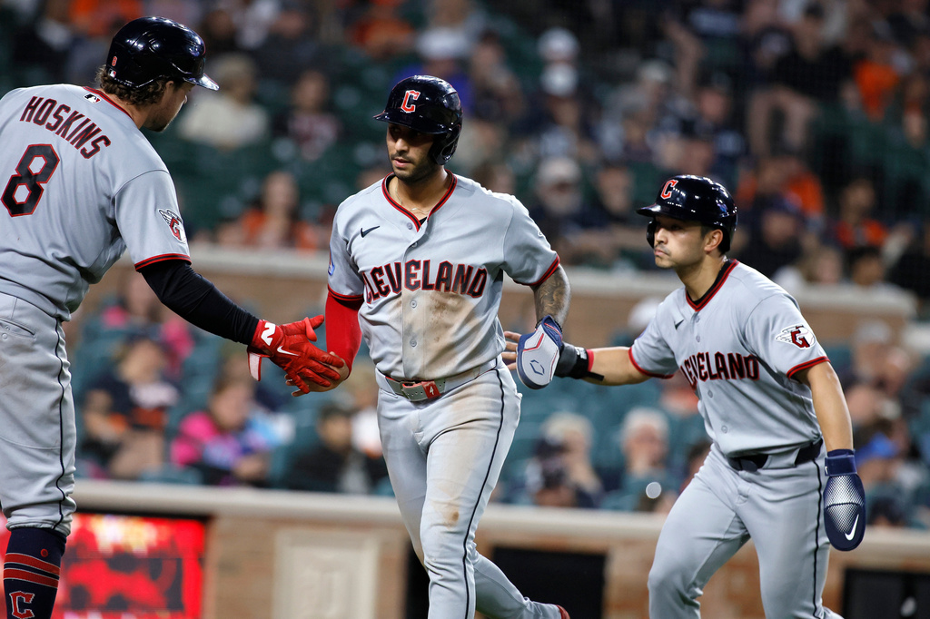 Cleveland Guardians' Brayan Rocchio, center, and Steven Kwan, right, celebrate with Rhys Hoskins (8) after scoring against the Detroit Tigers on a double by Jose Ramirez during the sixth inning of a baseball game, Monday, May 18, 2026, in Detroit. (AP Photo/Duane Burleson)