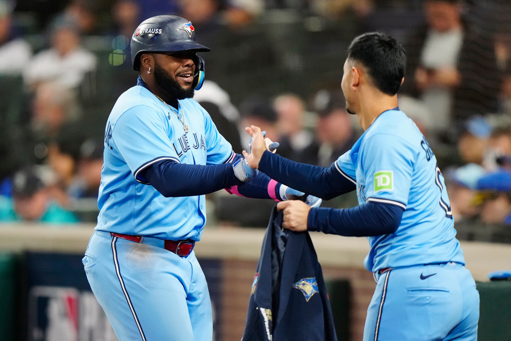 Toronto Blue Jays' Vladimir Guerrero Jr., left, celebrates with Andres Gimenez (0) after hitting a solo home run against the Seattle Mariners during fifth inning Game 3 American League Championship Series baseball action in Seattle on Wednesday, Oct. 15, 2025. (Frank Gunn/The Canadian Press via AP)