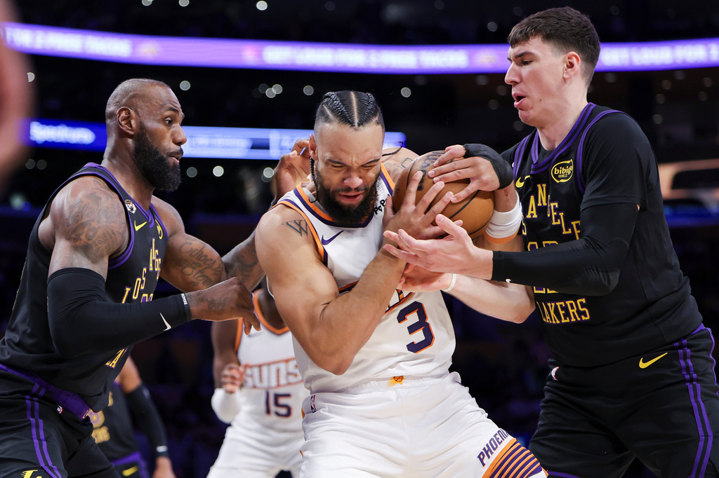 Phoenix Suns forward Dillon Brooks, center, Los Angeles Lakers forward LeBron James, left, and Lakers forward Jake LaRavia, right, battle for the ball during the first half of an NBA basketball game, Friday, April 10, 2026, in Los Angeles. (AP Photo/Jessie Alcheh)
