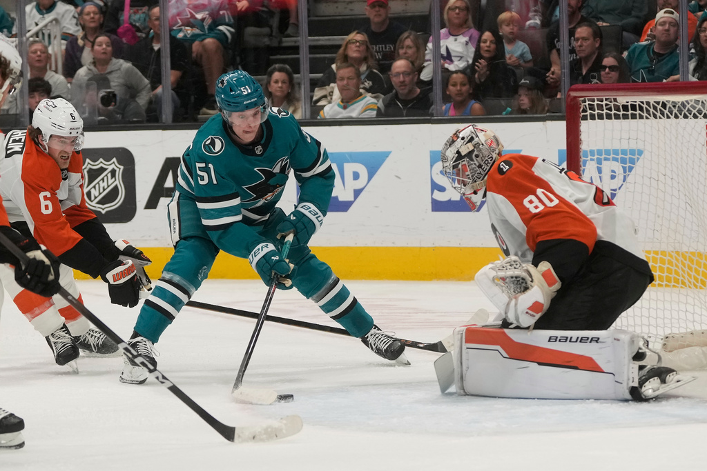 San Jose Sharks right wing Collin Graf (51) skates with the puck against Philadelphia Flyers defenseman Travis Sanheim (6) and goaltender Dan Vladar (80) during the first period of an NHL hockey game in San Jose, Calif., Saturday, March 21, 2026. (AP Photo/Jeff Chiu)