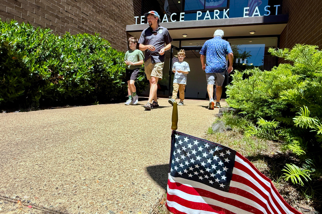 John Query leaves a polling place with his stepsons after voting Tuesday May 12, 2026, in Charleston, W.Va. (AP Photo/John Raby)