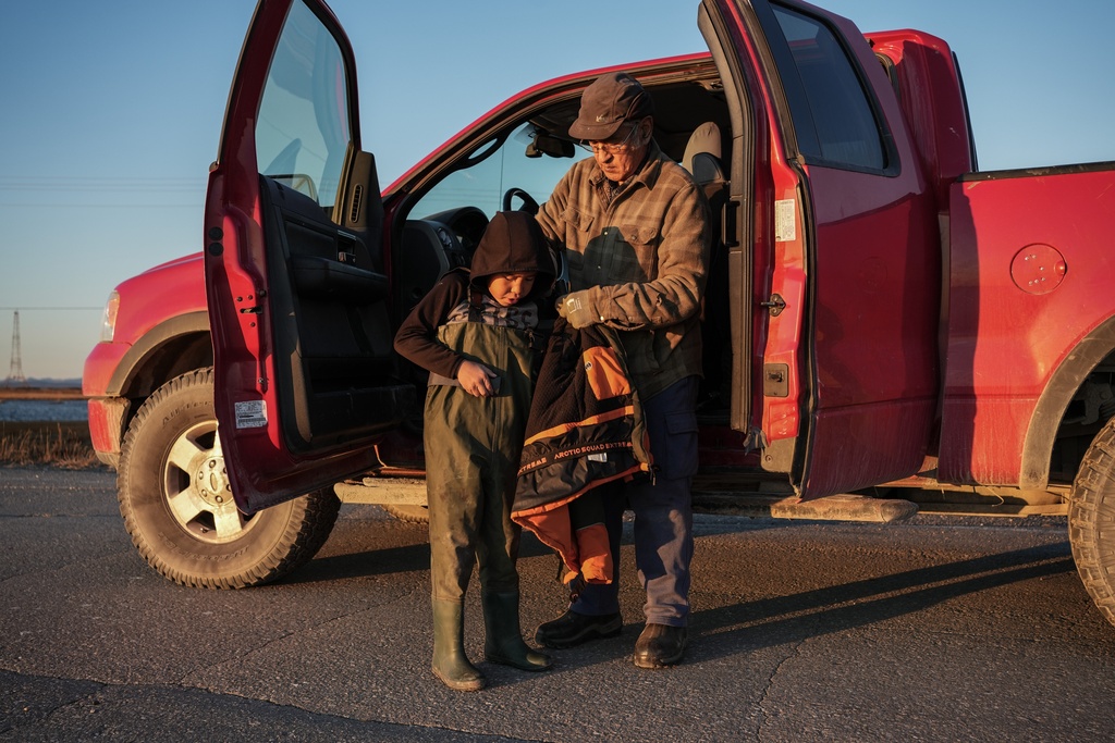 Roswell Schaeffer, an Inupiaq hunter and fisher, helps his great-grandson James Schaeffer, 7, into waders while hunting Friday, Sept. 26, 2025. (AP Photo/Annika Hammerschlag)