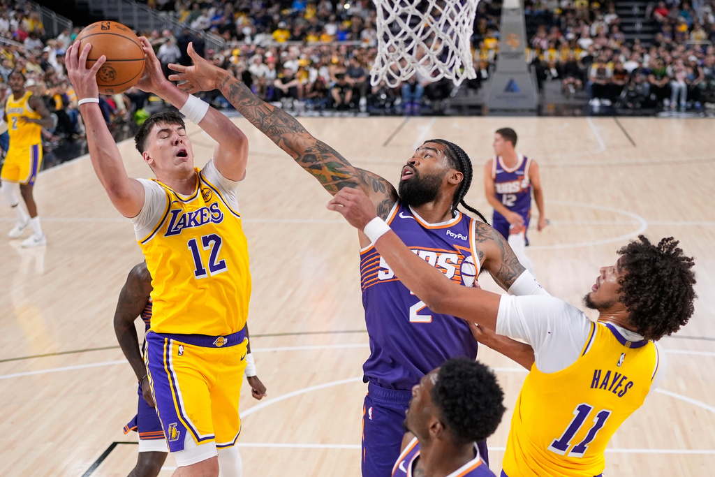 Los Angeles Lakers forward Jake LaRavia, left, grabs a rebound away from Phoenix Suns center Nick Richards, center, as center Jaxson Hayes reaches in during the first half of an NBA preseason basketball game Friday, Oct. 3, 2025, in Palm Desert, Calif. (AP Photo/Mark J. Terrill)