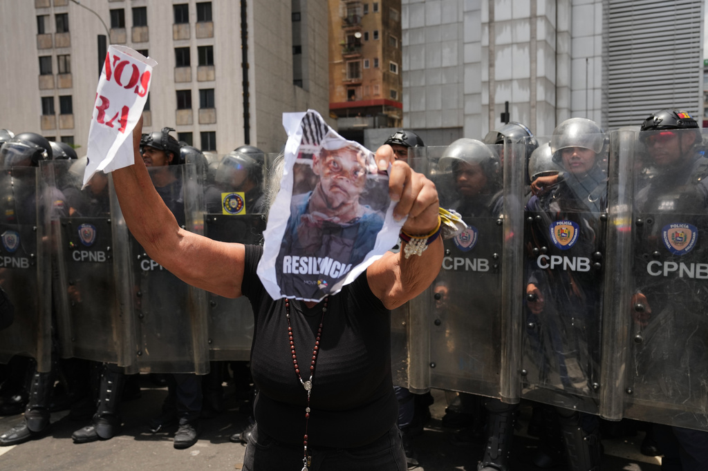A woman holds an image of Carmen Navas during a protest calling for justice the day after her death in Caracas, Venezuela, Monday, May 18, 2026, a week after the government confirmed that her missing son Victor Hugo Quero had died in custody following his arrest about a year earlier. (AP Photo/Ariana Cubillos)