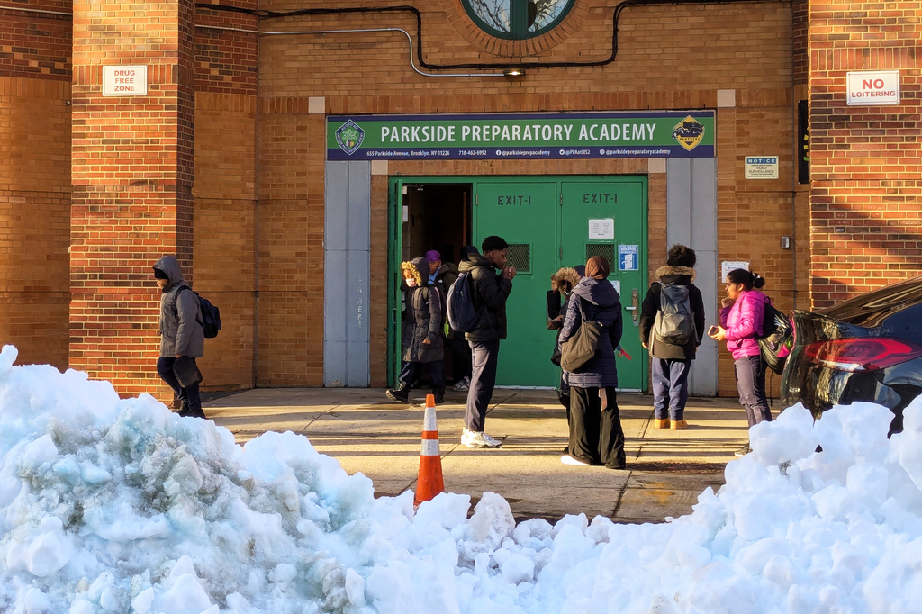 Children stand outside the doors of Parkside Preparatory Academy a day after a snowstorm in the borough of Brooklyn, New York, on Tuesday, Feb. 24, 2026. (AP Photo/Drew Callister)