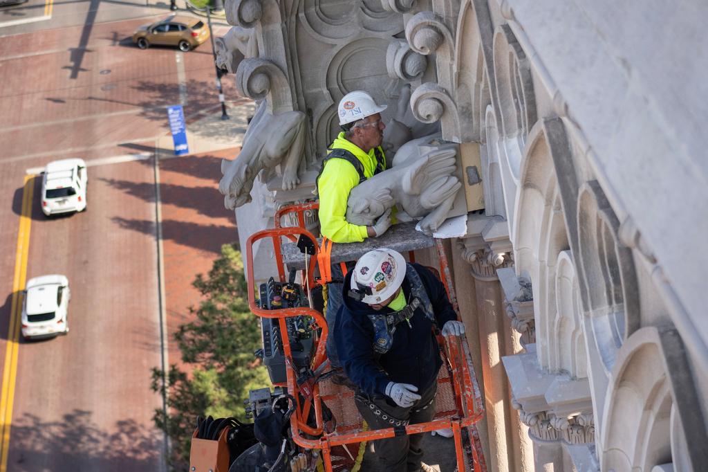 The final new terra cotta gargoyle is installed by Cole Burklund, top, and Blake Priest using a cherry picker high on the Cathedral Basilica of the Assumption, known as "America's Notre Dame," in Covington, Ky., on Monday, March 30, 2026. (AP Photo/Carolyn Kaster)