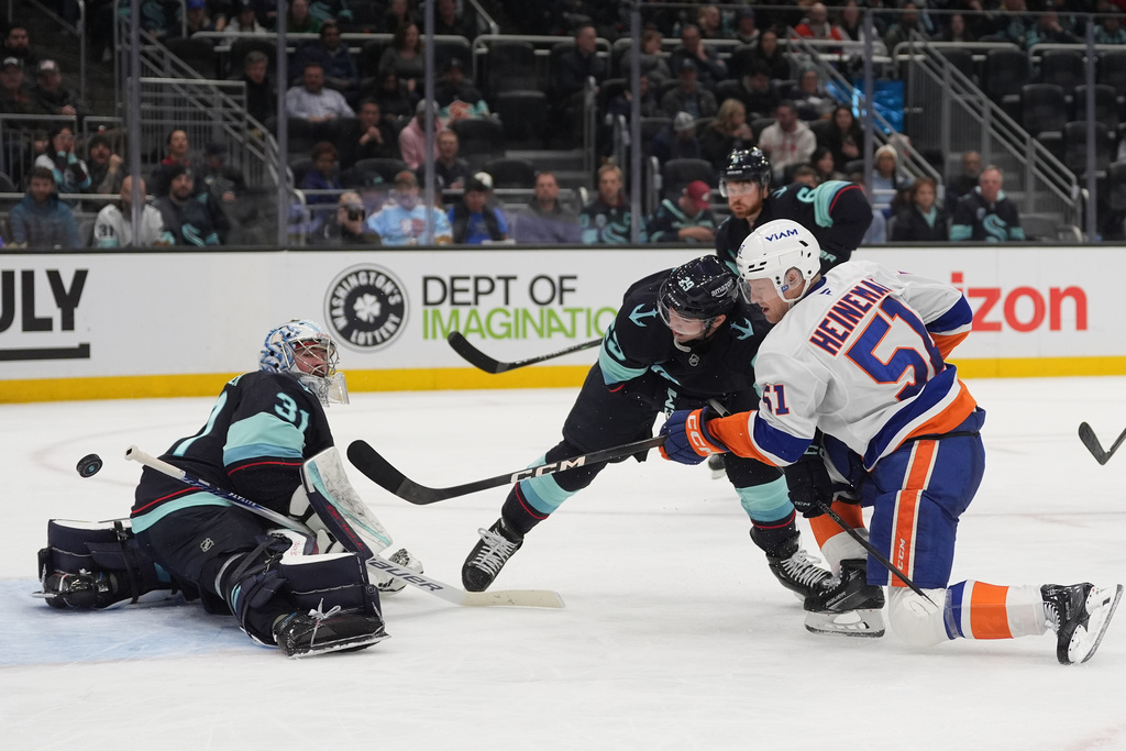 New York Islanders left wing Emil Heineman (51) makes a shot against Seattle Kraken goaltender Philipp Grubauer (31) as defenseman Vince Dunn (29) looks on during the second period of an NHL hockey game Wednesday, Jan. 21, 2026, in Seattle. (AP Photo/Lindsey Wasson)