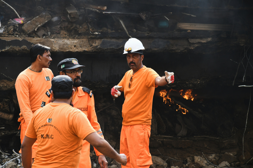 Firefighters search through the rubble of a burnt building of a multistory shopping plaza following a massive fire in Karachi, Pakistan, Monday, Jan. 19, 2026. (AP Photo/Ali Raza)